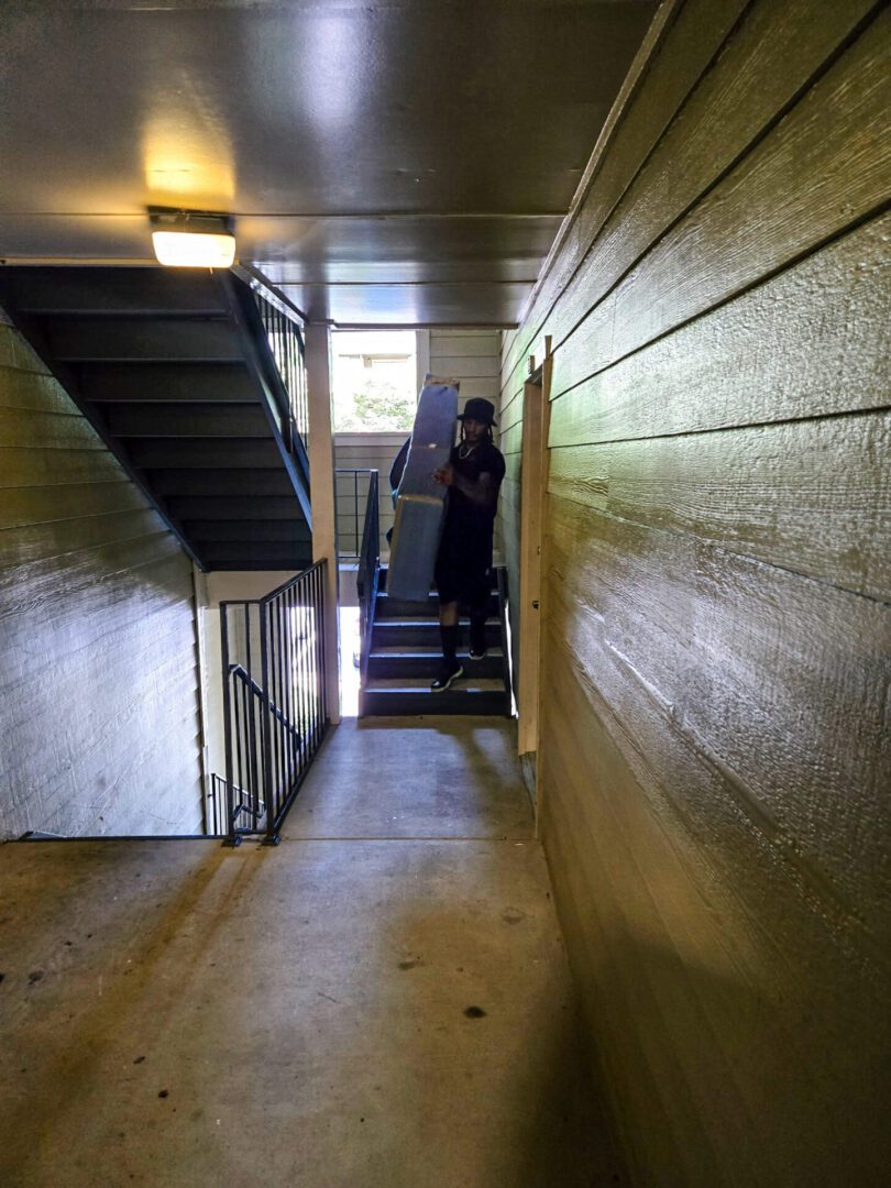Person carrying box up apartment stairs.