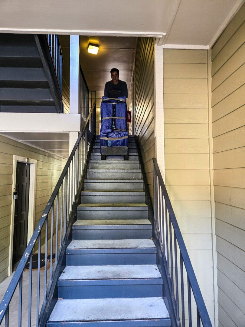 Person moving items down apartment stairs.