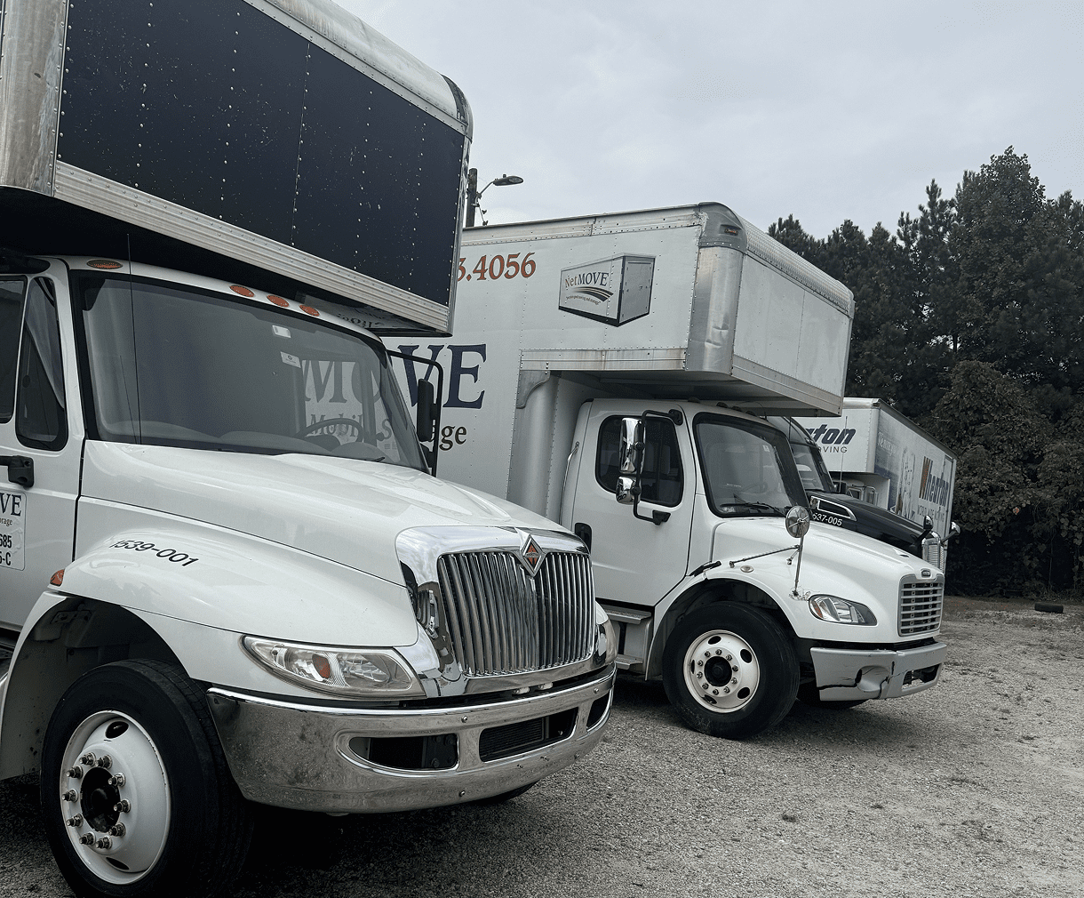 Two white moving trucks parked outside.