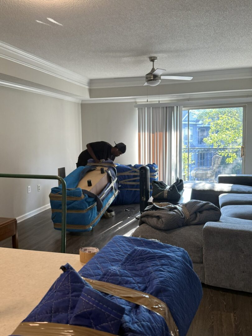 Person wrapping furniture in a living room.