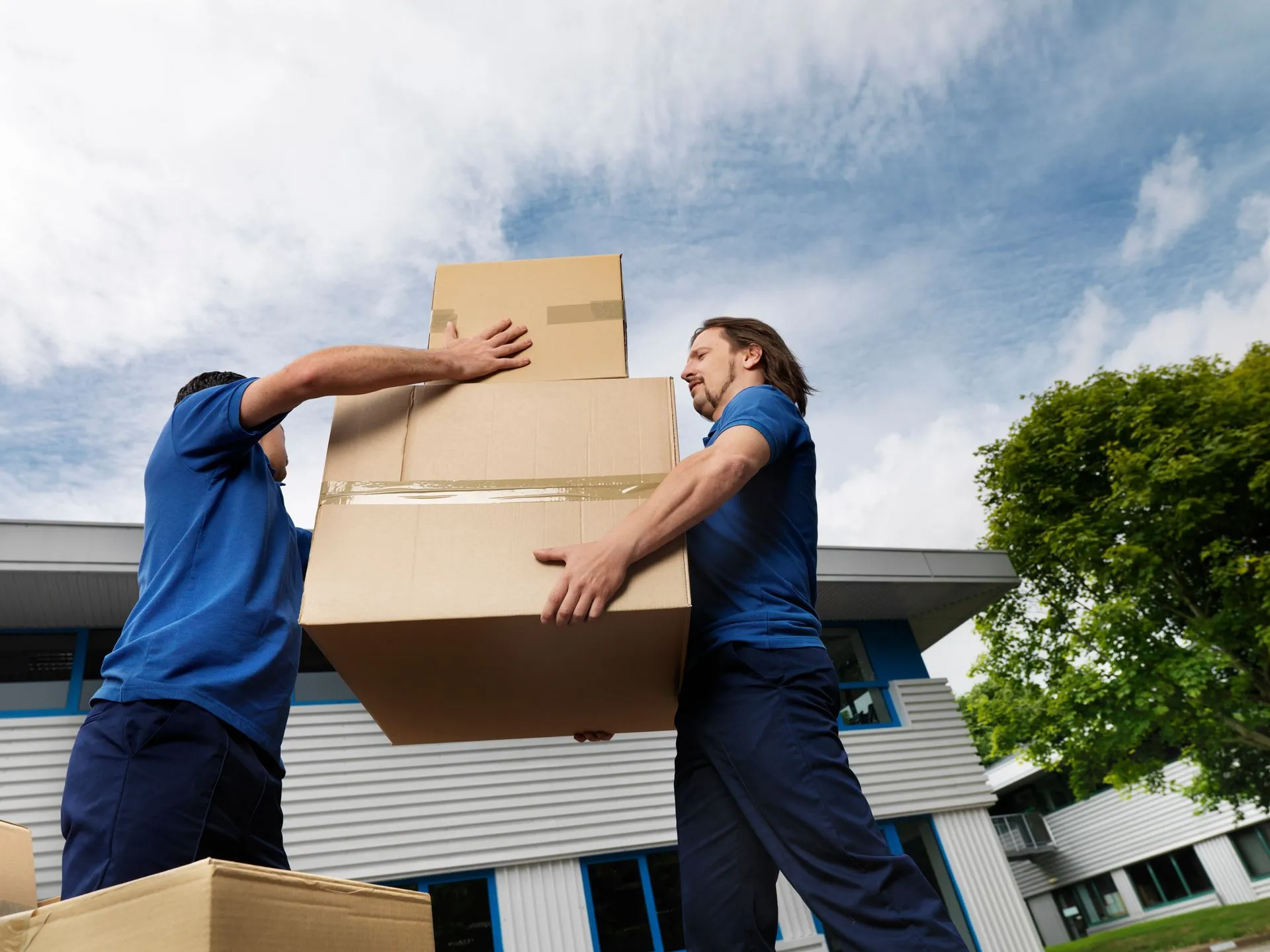 Workers carrying boxes outside a building.