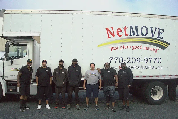 Moving company team in front of truck.