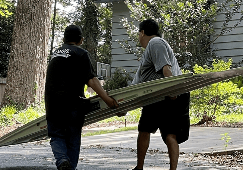 Two people carrying a large metal sheet.
